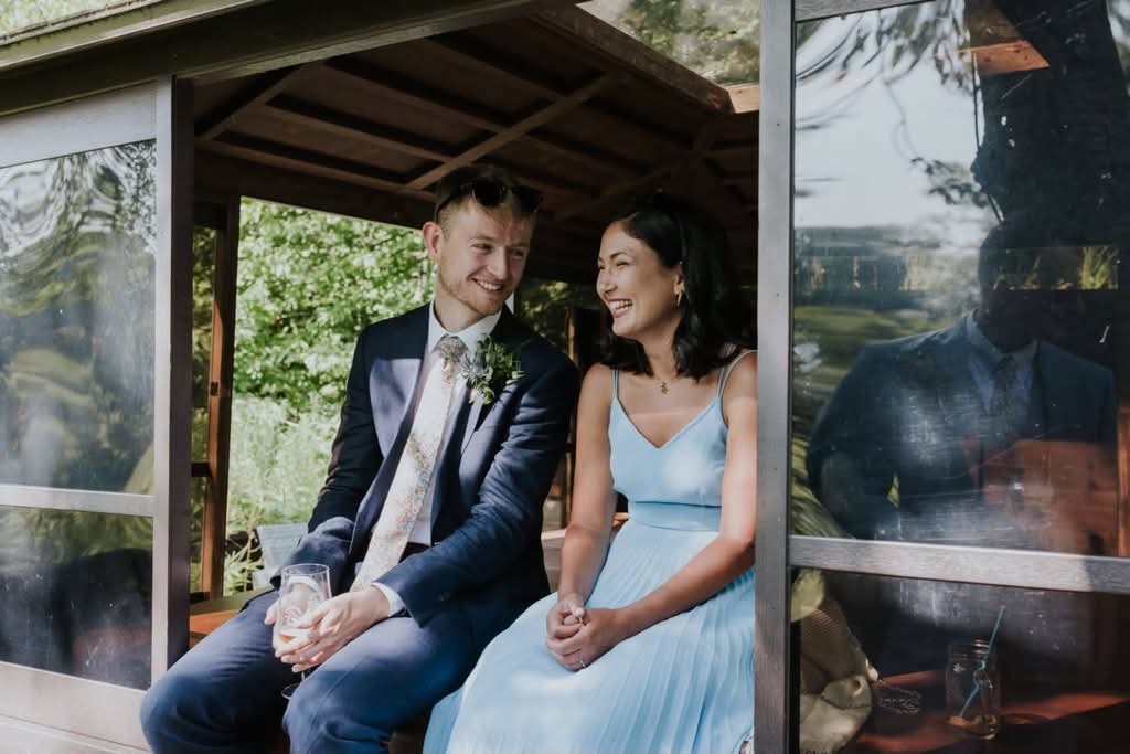 Luisa and Tom laughing in a garden pavilion